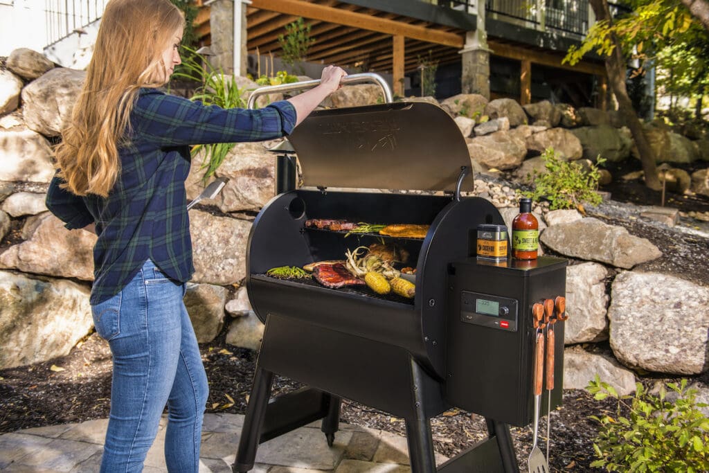 A woman cooks some festive fall recipes on her backyard Traeger grill