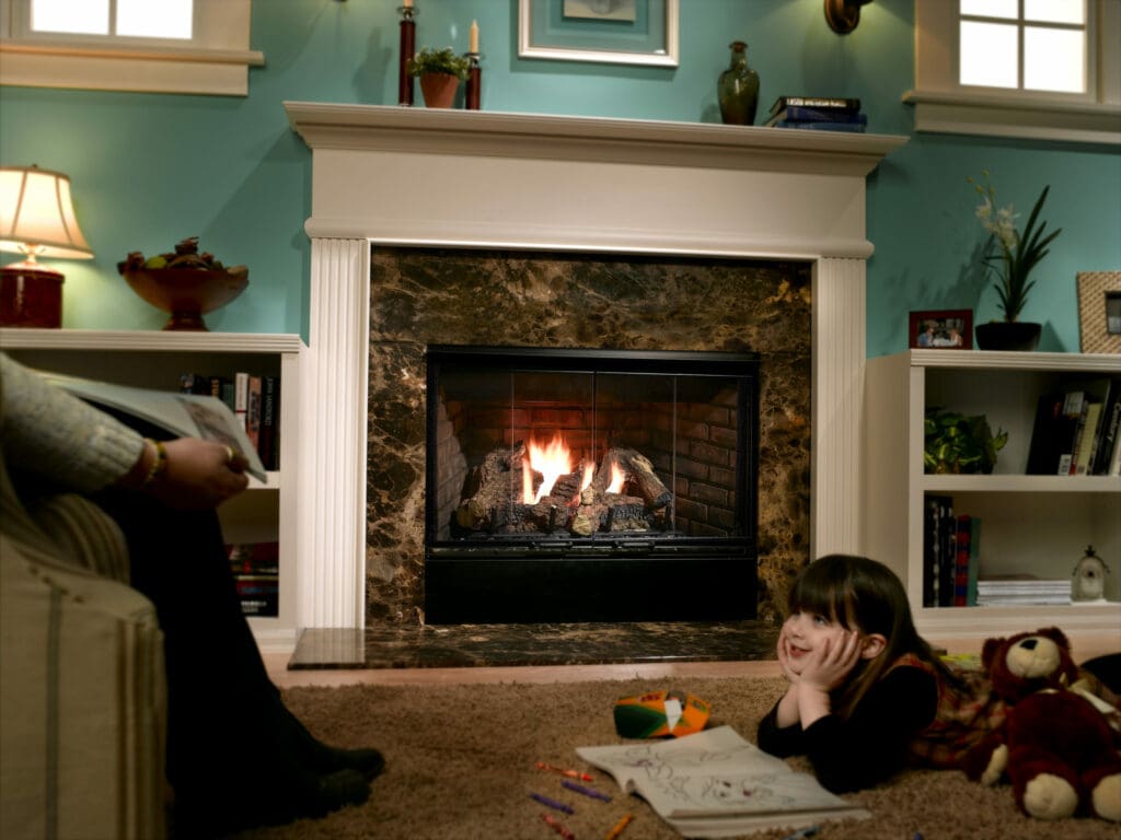 A young girl child enjoys coloring by a safely lit fireplace